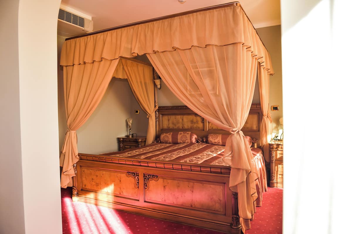 Een hemelbed met een houten frame en rode beddengoed.
