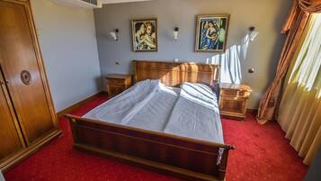 A hotel room with a wooden bed, two bedside tables, a wardrobe, and two wall-mounted lamps.