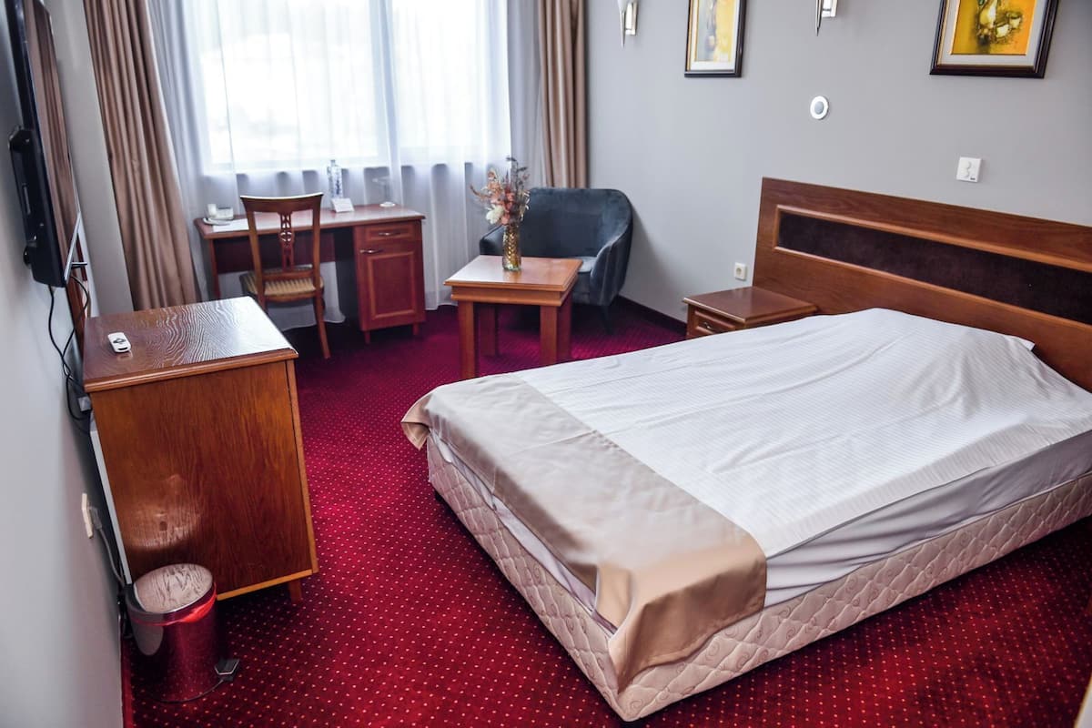 Een hotelkamer met een groot bed, een bureau, een stoel en een kleine tafel.