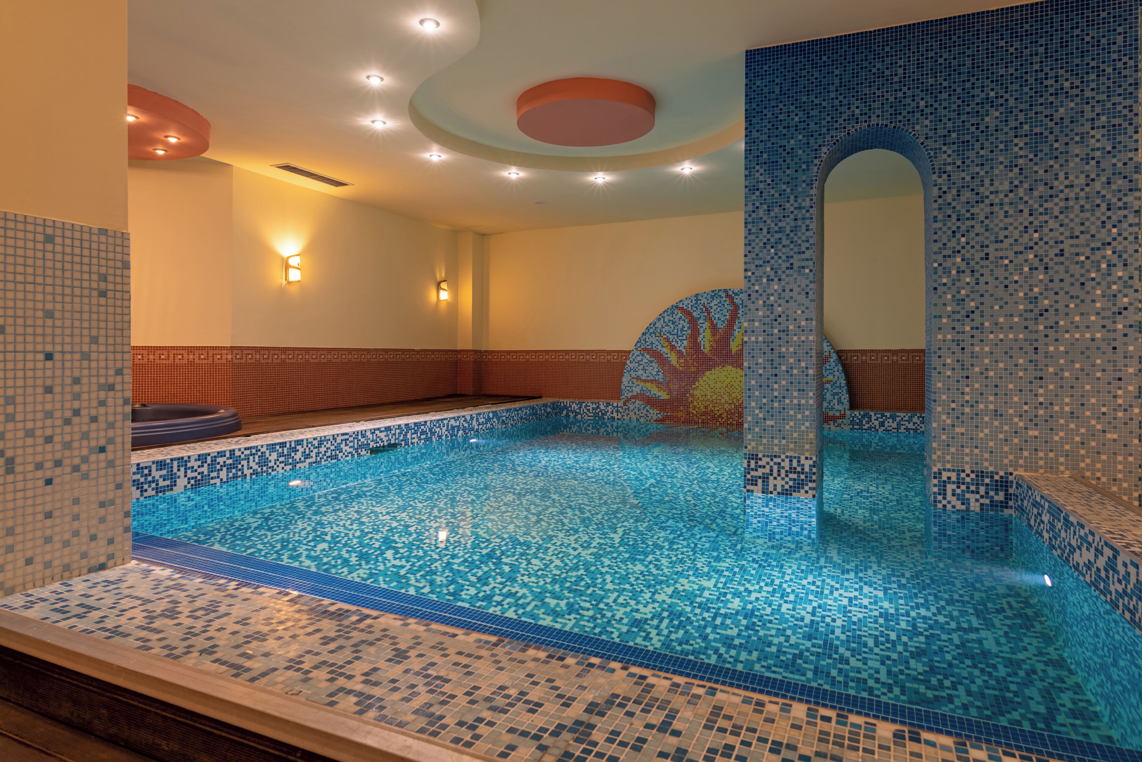 A swimming pool with mosaic tile walls and a clear blue water surface.