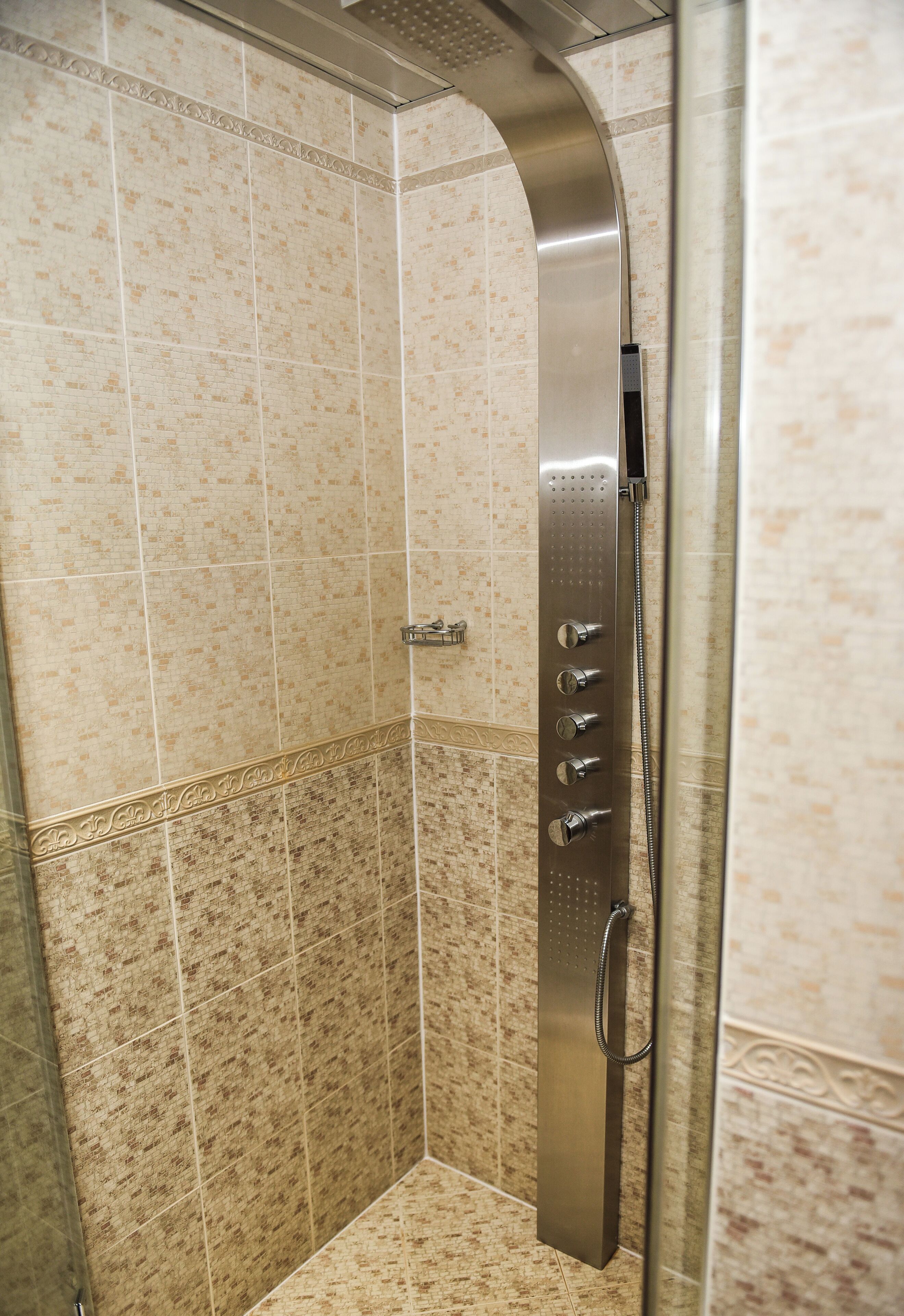 Cabina de ducha con ducha de diseño curvo y varios controles de agua.