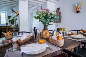 A breakfast setting with a wooden table, wicker baskets, and a vase of flowers. - Villa N1 Saint-Émilion (Saint-Émilion)