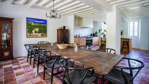 A spacious dining area with a large wooden table and black chairs, a chandelier, and a painting on the wall. - Villa N1 Saint-Émilion (Saint-Émilion)