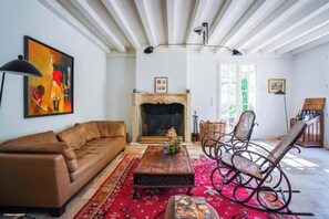 A living room with a brown leather sofa, a wooden coffee table, and wicker rocking chairs. - Villa N1 Saint-Émilion (Saint-Émilion)