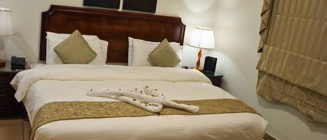 A neatly made bed with a brown headboard, white bedding, and a folded towel.