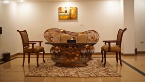 A dining area with a round table, four chairs, and a decorative wall piece. - Sand Rose Suite Hotel (Al Khobar)