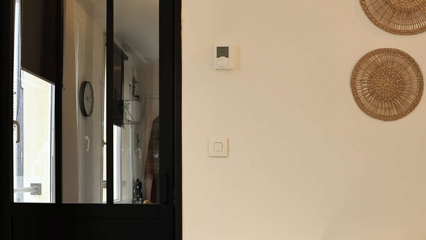 Ein gemütliches Wohnzimmer mit einem weißen Sofa, einem runden Beistelltisch mit Lampe und einem großen Spiegel an der Wand.