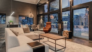 A modern living room with a large sofa, a coffee table, and a fireplace. - Villa Ailo - Quality Villa with Sauna & Jacuzzi (Kuusamo)