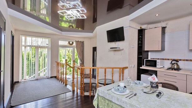 A dining area with a table set for two, a kitchen with modern appliances, and a staircase leading to an upper level.