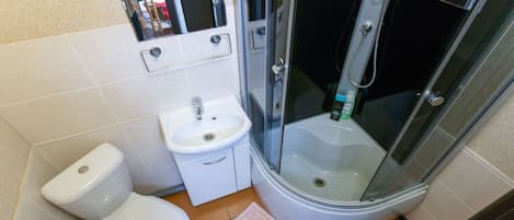 Un baño pequeño con inodoro, lavamanos y ducha con mampara de vidrio.