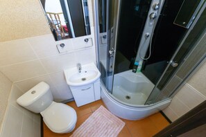 A compact bathroom with a toilet, sink, and glass-enclosed shower.