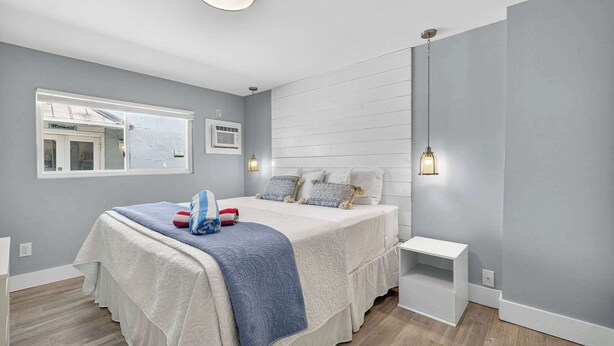 Um quarto moderno com uma cama grande, mesas de cabeceira, uma janela e um lustre.