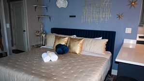 A neatly made bed with a tufted headboard, a bedside table, and a wall with decorative elements.