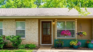 A stone house with a front door, windows, and hanging flower baskets. - Spacious 3BR SoCO Family stay❤️ Big Private Yard with Firepit | Minutes to Dtwn (Austin)