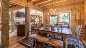 A wooden interior with a stone pillar, a wooden table, and a bench. - Mamas Mountain Place -custom home, pet friendly, hot tub, large entertain room with foosball, pond (Seven Devils)