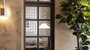 Una puerta con paneles de vidrio esmerilado, un picaporte y una lámpara en la pared.