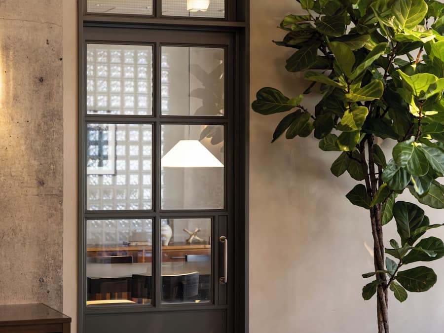 A door with frosted glass panels, a handle, and a light fixture on the wall.