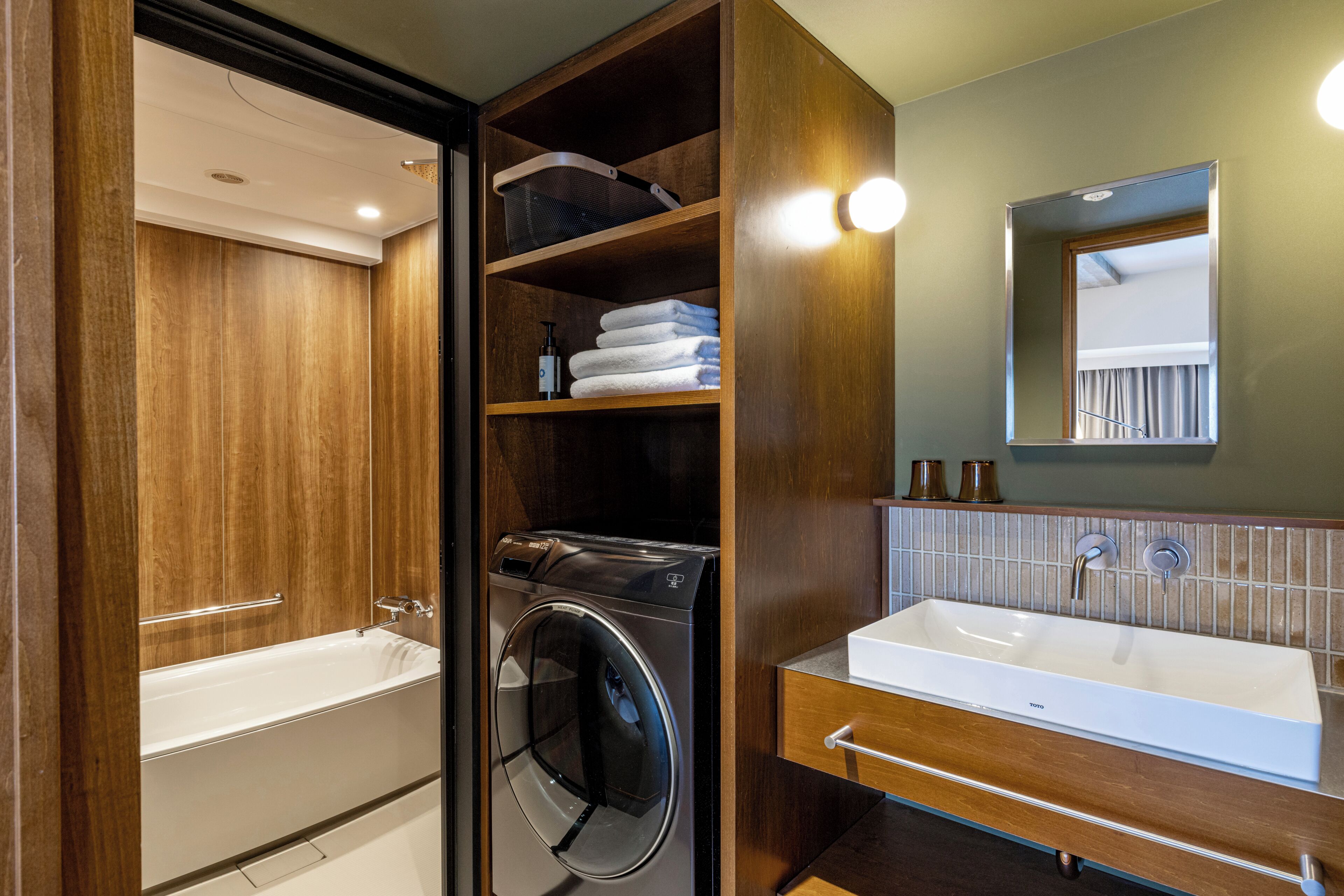 A modern bathroom with a built-in washing machine, a large sink, and wooden cabinetry.