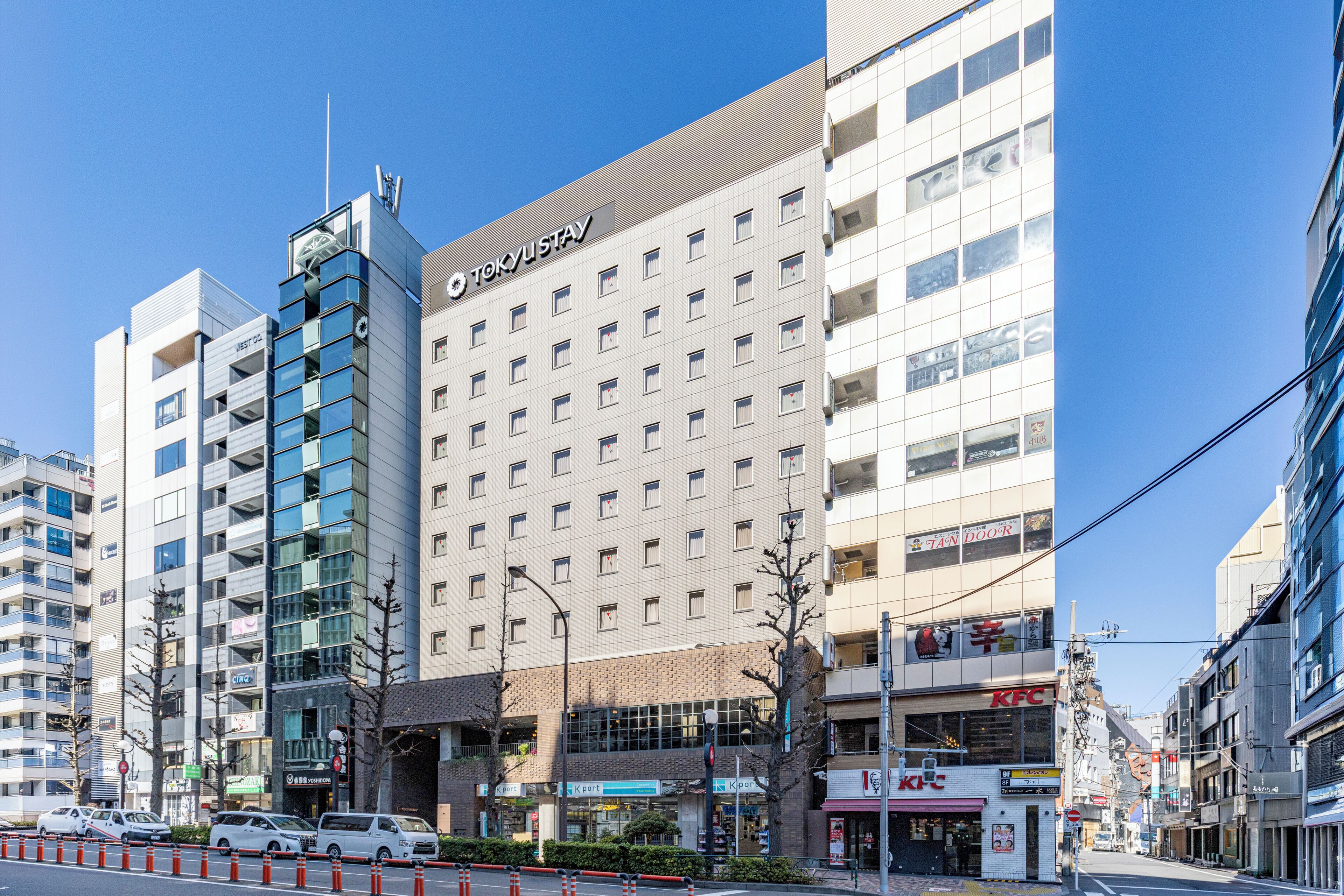 Um hotel de vários andares com fachada moderna, várias varandas e uma placa chamativa para 'TOKYU STAY'.