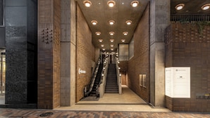 Un edificio moderno con una escalera central, un cartel y una pared de ladrillo.