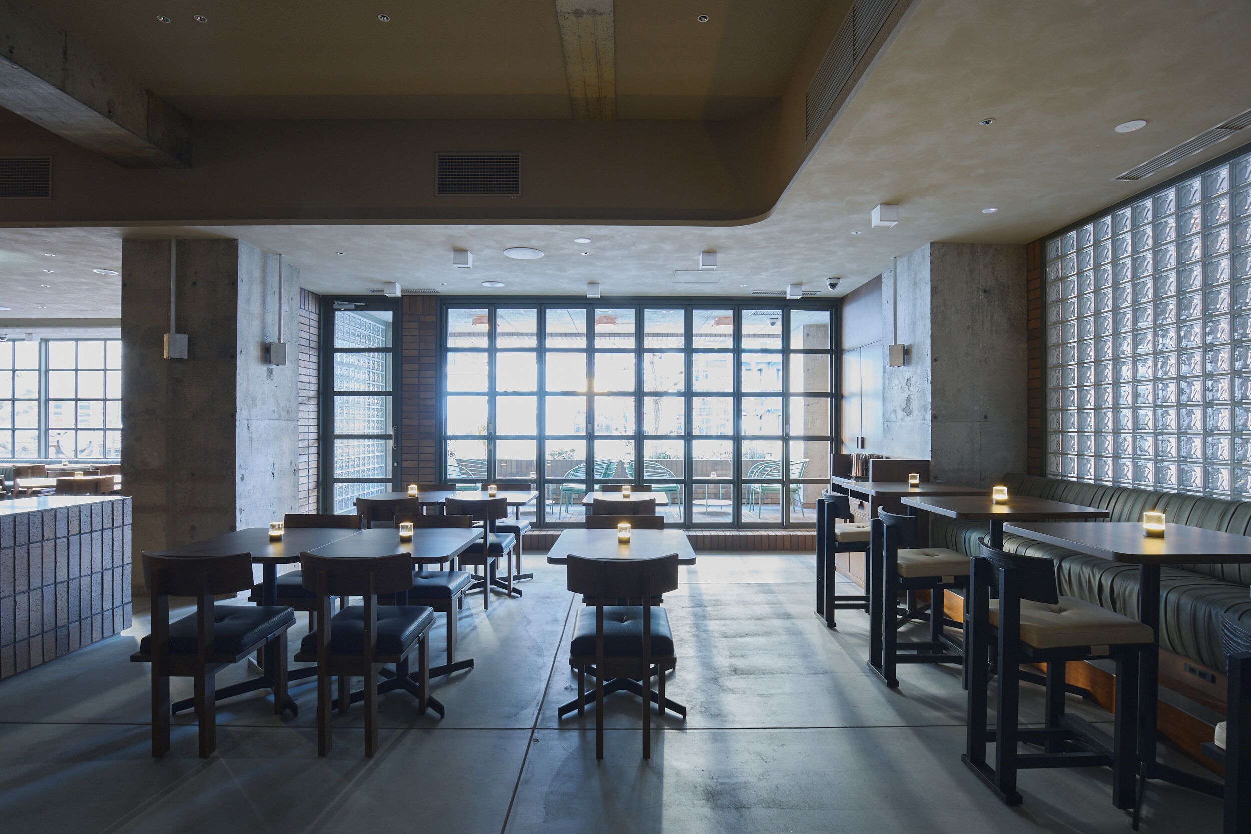 A modern restaurant with high ceilings, large windows, and a mix of seating arrangements including tables and booths.