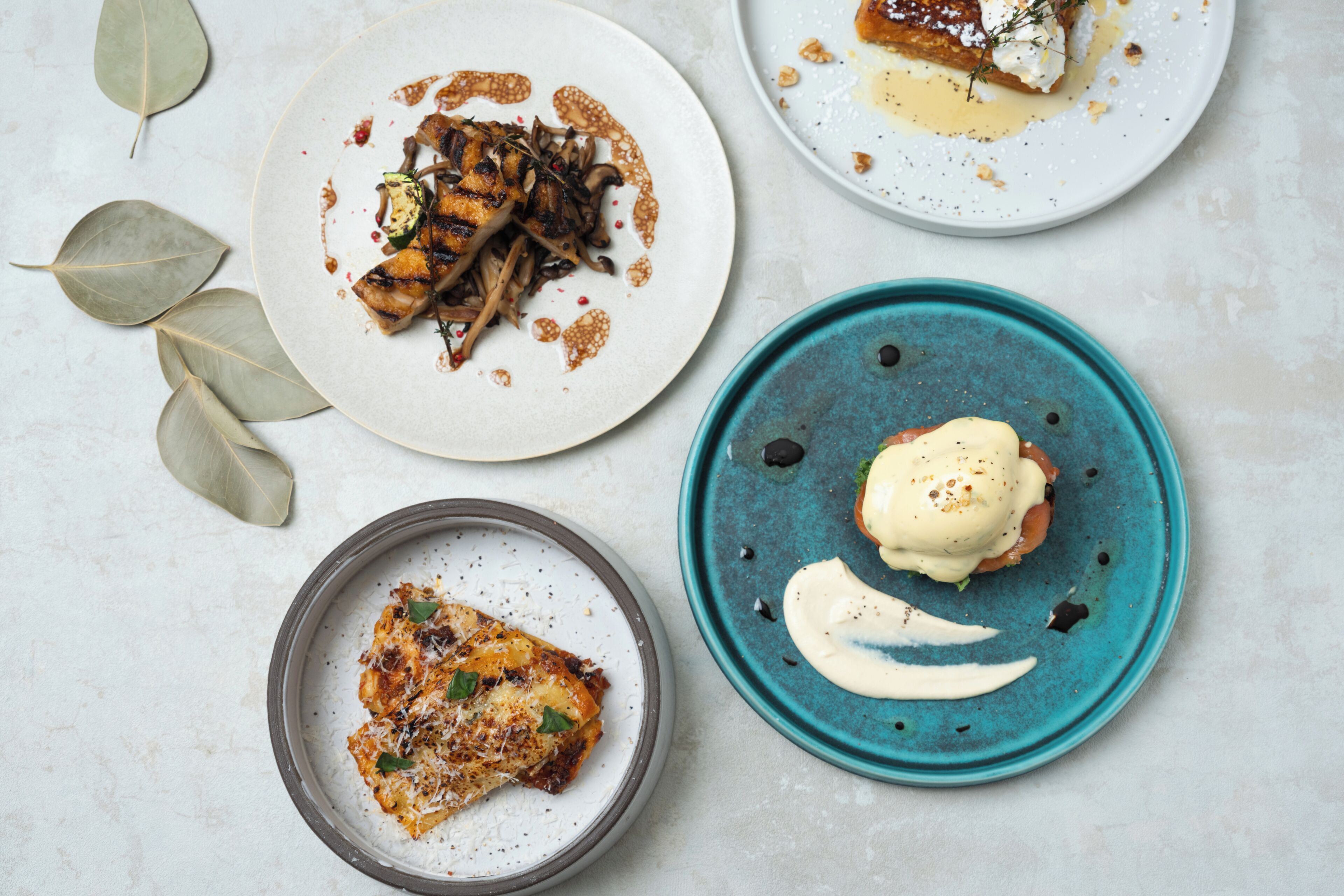 Four plates of food with various dishes and garnishes.