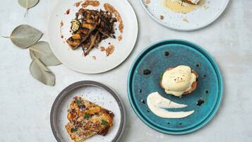 Four plates of food with various dishes and garnishes.