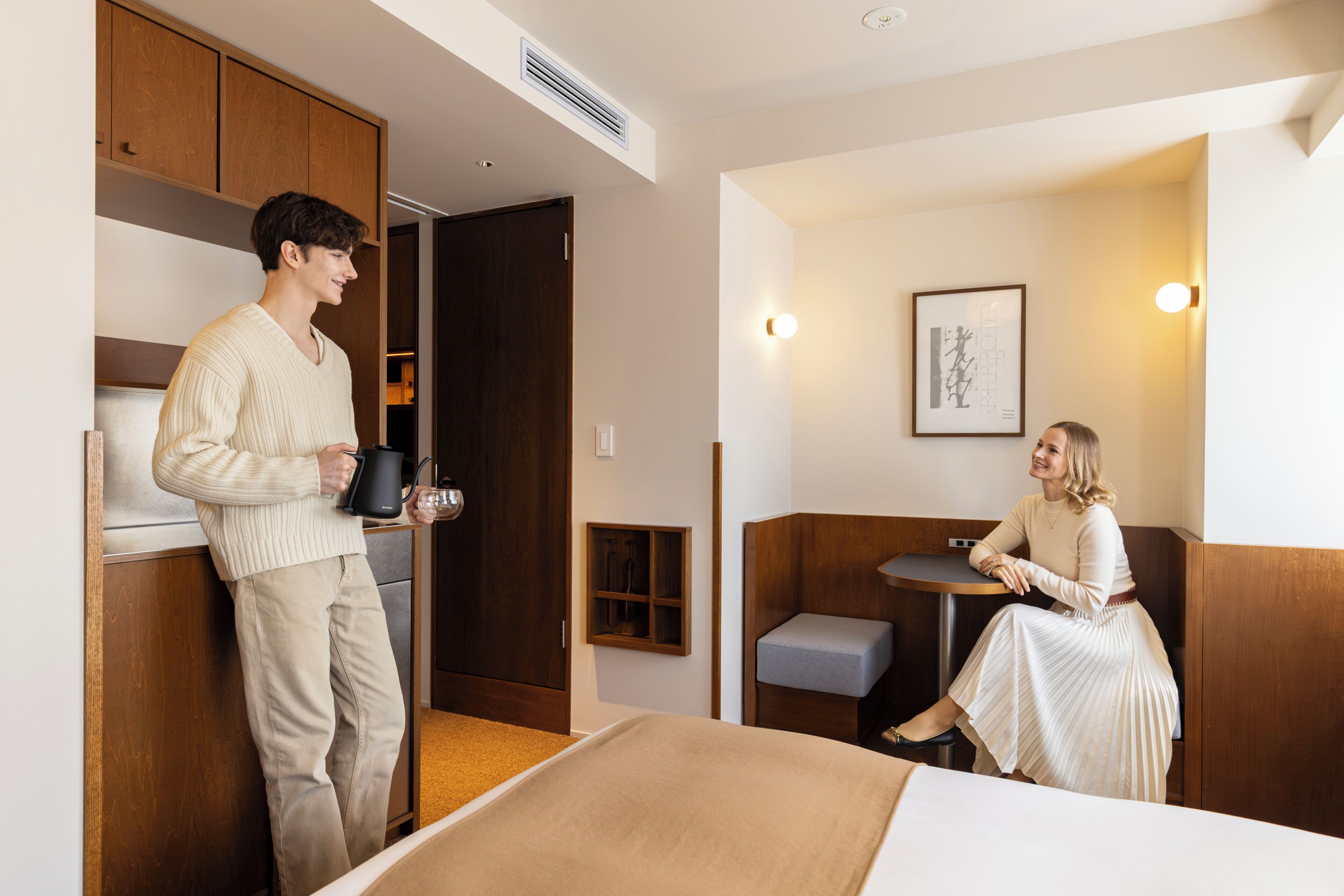 Une chambre d’hôtel comprenant un lit, une petite table, un coin salon et une kitchenette.