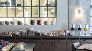 Una cocina moderna con un amplio ventanal, electrodomésticos de acero inoxidable y una variedad de recipientes y cuencos sobre la encimera.
