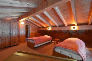 A room with two beds, wooden walls, a wooden ceiling, and a small stool. - Chalet 'Lo Capstoa' with Mountain View, Private Terrace and Wi-Fi (Hauteluce)