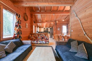 A cozy cabin interior with a sofa, a coffee table, and a dining area. - Chalet 'Lo Capstoa' with Mountain View, Private Terrace and Wi-Fi (Hauteluce)