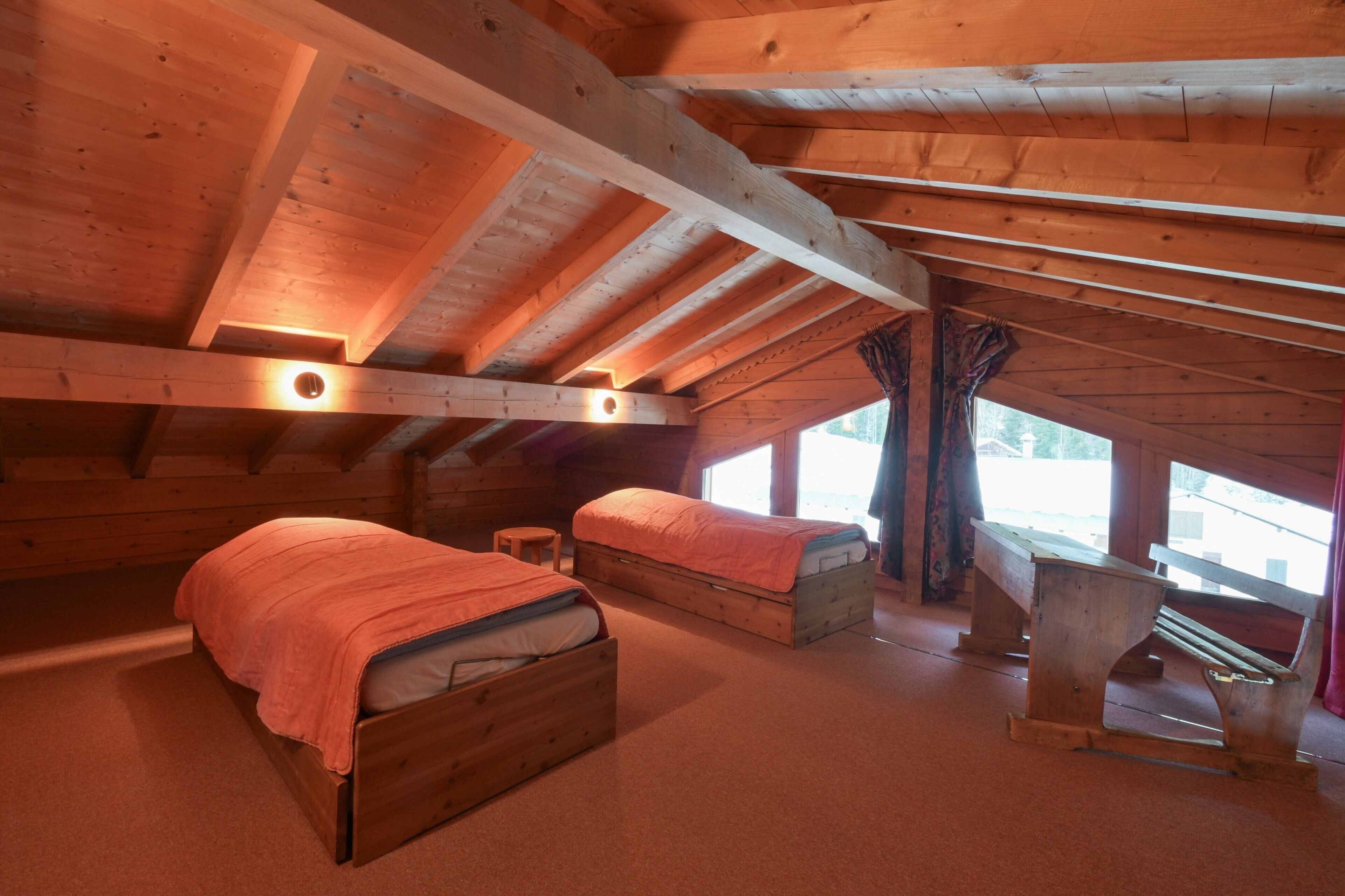 A wooden cabin with two wooden beds, a bench, and a window with curtains.