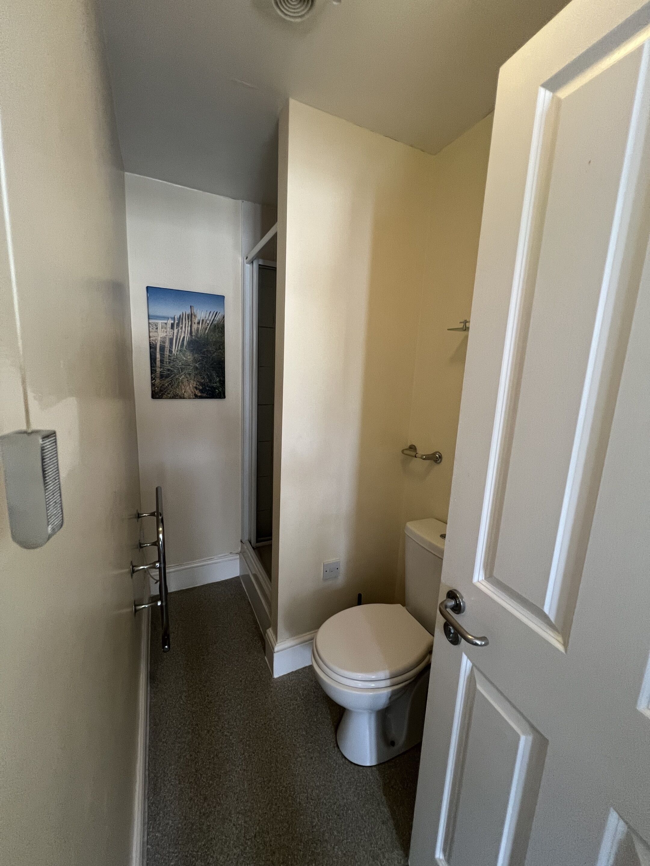 Un baño pequeño con inodoro, ducha y puerta.