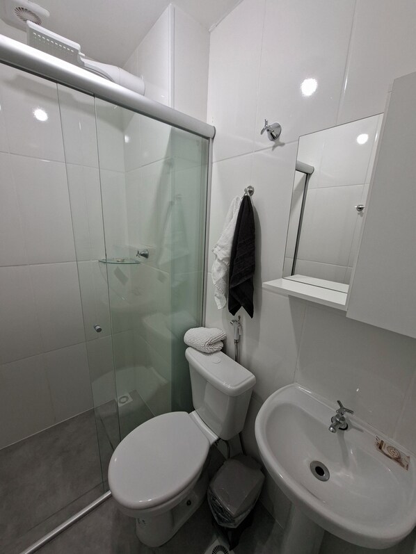 Un baño moderno con cabina de ducha de vidrio, inodoro, bidé y lavamanos.