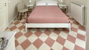 Un dormitorio con cama, una silla, una mesita de noche, una lámpara y un radiador.