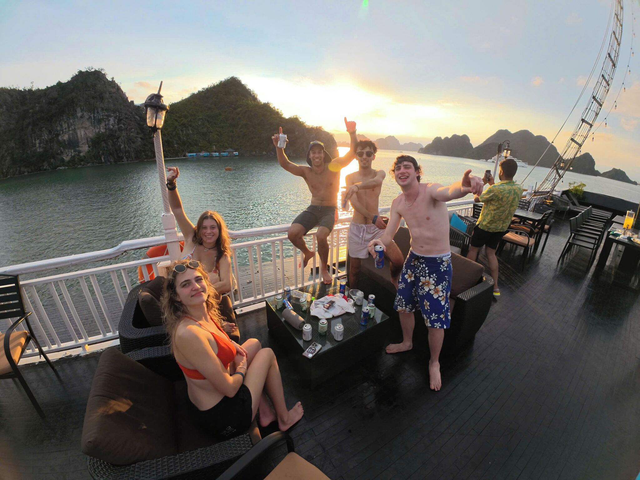 A group of people on a boat deck with a view of the water and hills in the background.