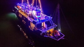 A large, illuminated boat with multiple decks and a central tower, likely used for tours or events. - Oasis Bay Party Cruise (Tuan Chau)