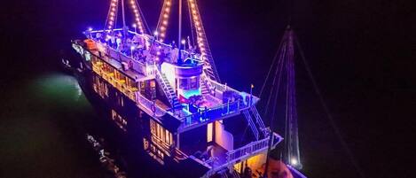 A large, illuminated boat with multiple decks and a central tower, likely used for tours or events.