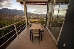 A balcony with a table and chairs, offering a view of a mountainous landscape. - Utopia Casas Boutique (Huajuapan)