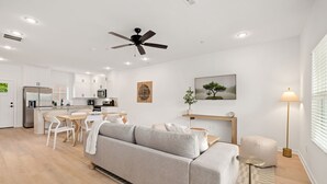 Un espacio habitable moderno y bien iluminado con sofá, mesa de comedor y zona de cocina.