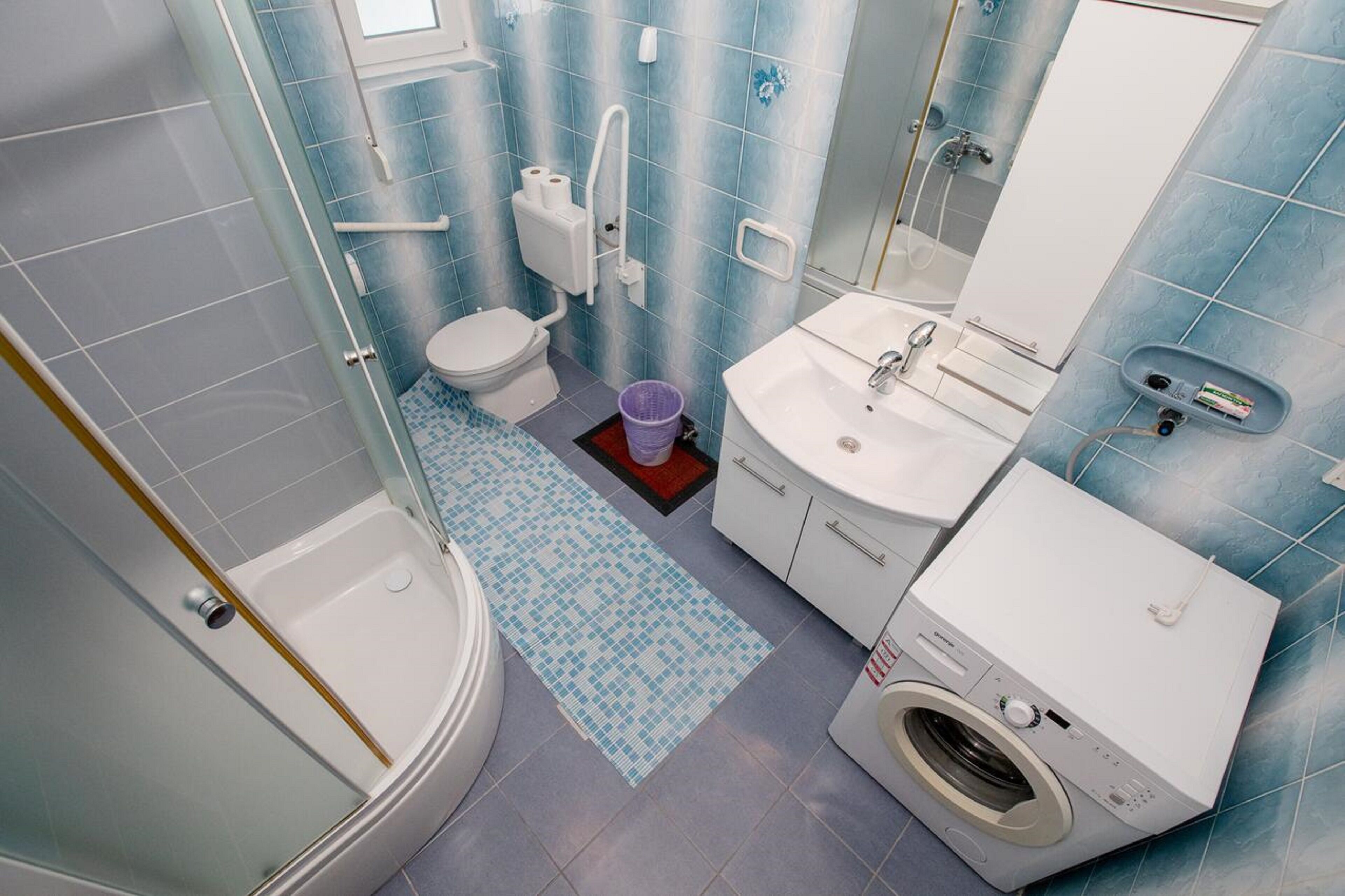 A bathroom with a bathtub, toilet, sink, and washing machine.