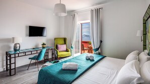 A hotel room with a bed, a desk with a chair, a television, and a view of the outdoors. - Villa Aprea - luxury villa with stunning views and private heated pool (Massa Lubrense)