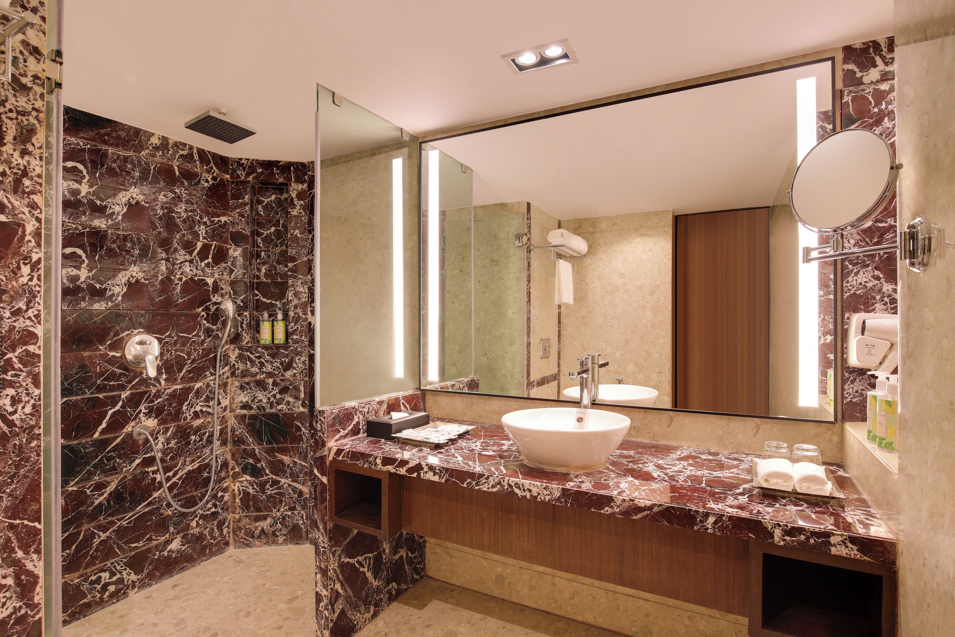 A modern bathroom with a marble vanity, a large mirror, and a glass-enclosed shower.
