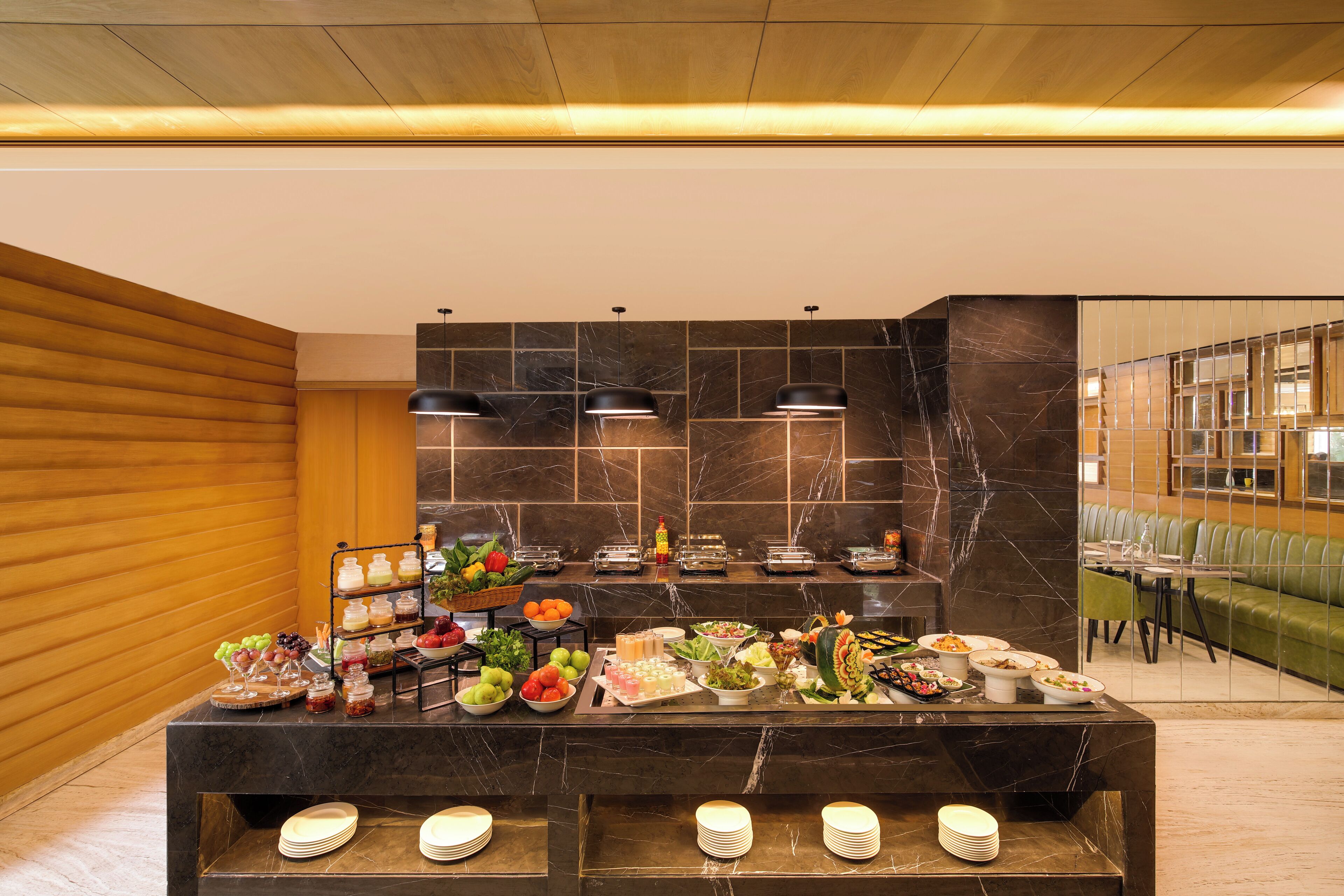 A buffet setup with various food items and a seating area with a green couch and tables.