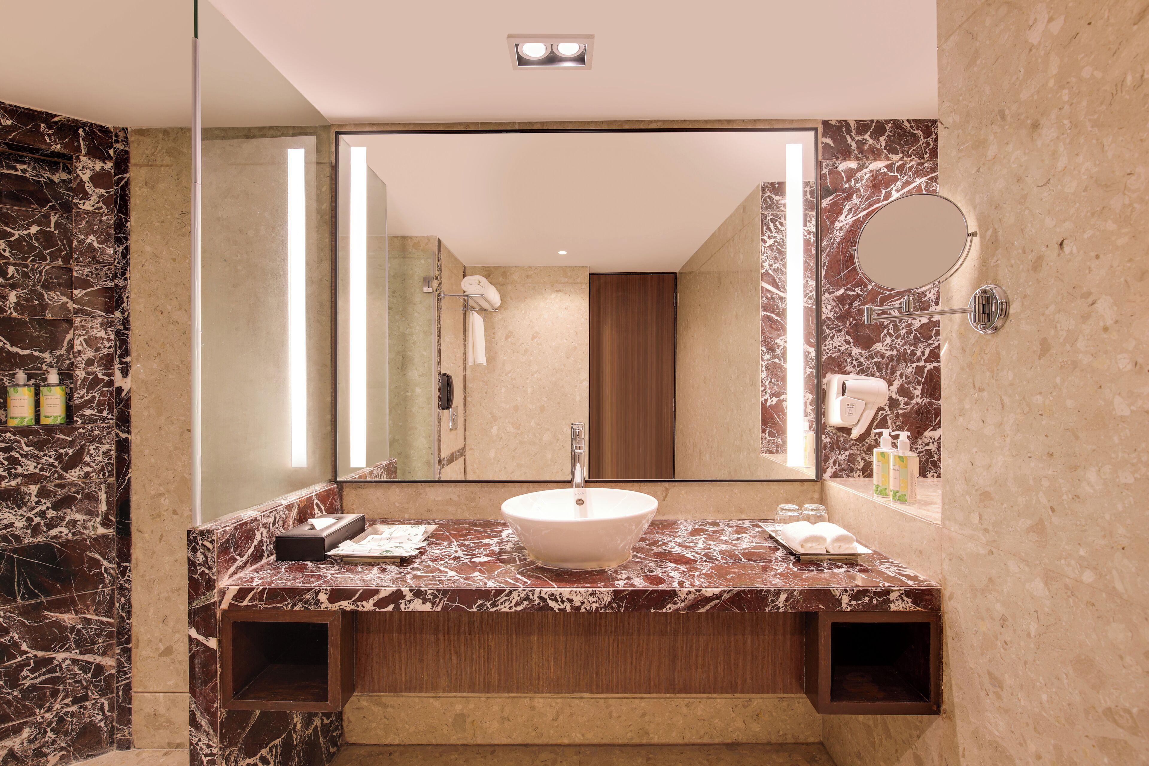Une salle de bain moderne avec un meuble-lavabo en marbre, un grand miroir et un lavabo encastré.