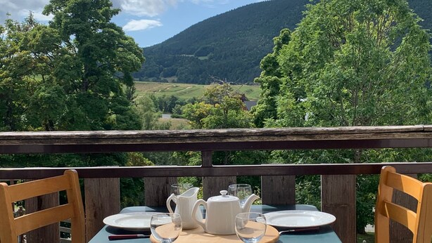 A table set for four with a view of a mountainous landscape.