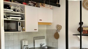 A kitchen with white cabinets, a built-in dishwasher, a coffee maker, and a sink.