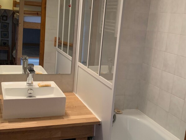 A bathroom with a white sink, a mirror, and a bathtub.