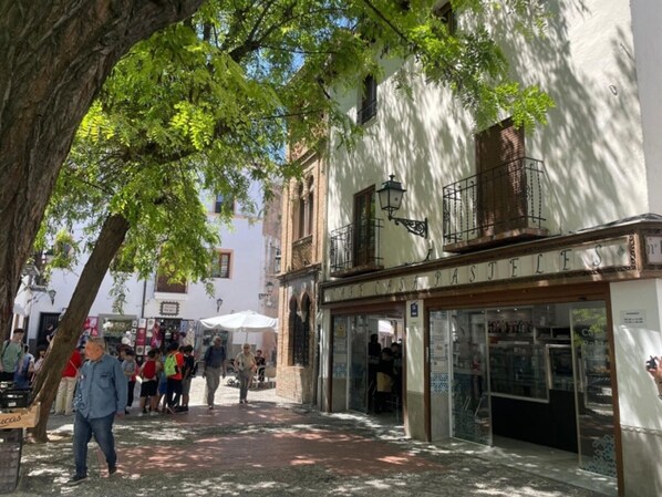 A street with buildings, a tree, and people walking.