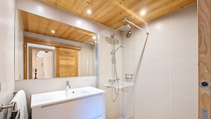 A modern bathroom with a wooden ceiling, a large mirror, a white sink, and a glass-enclosed shower. - Apartment 6 pers, 2 bdr, 54 m², garage, La Clusaz (La Clusaz)